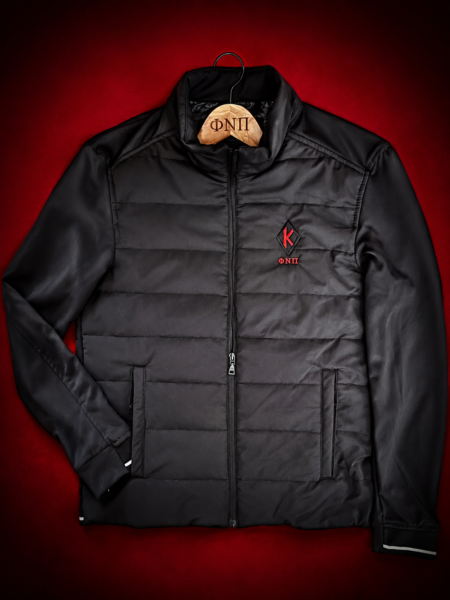 Custom embroidered black hybrid quilted performance jacket with crimson diamond insignia and Greek letter abbreviation on left chest, reflective cuff and hem details, multi-pocket system.