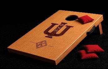 Mini wood bag toss board engraved with Greek letters, with red toss bags beside it